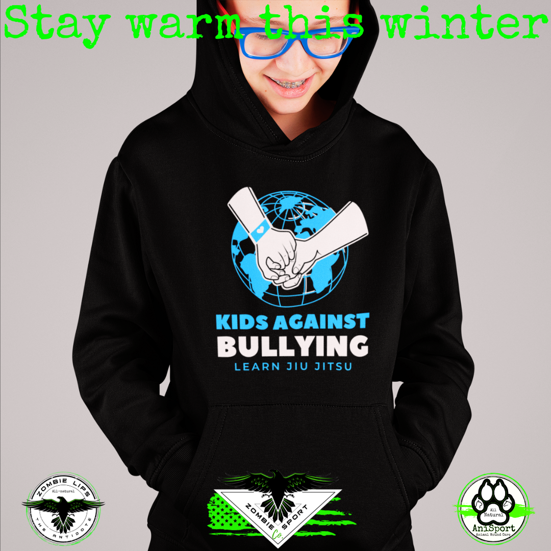 Model wearing Zombie Sport Co’s black Kids Against Bullying hoodie with a blue-and-white globe graphic and Learn Jiu Jitsu text.